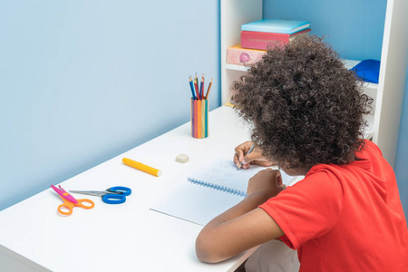 黑人男孩在笔记本上写字.孩子坐在书桌前做作业.学校孩子教育理念照片