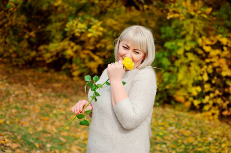 中年妇女在秋天的户外摆姿势她站在一棵白桦树旁黄叶子穿着红色外套开