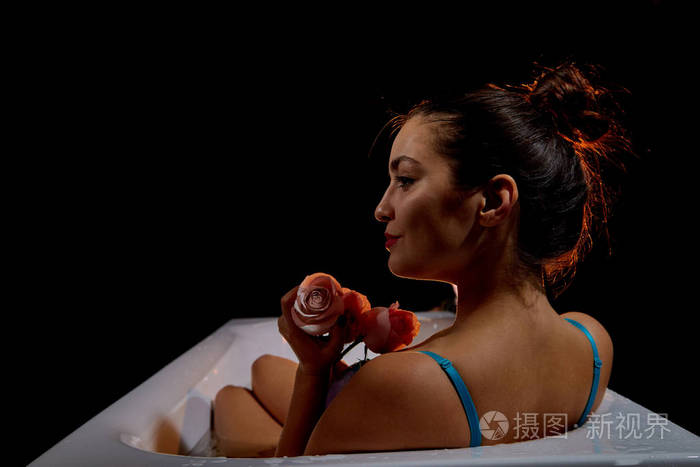 一个年轻漂亮的黑发女人在黑暗的房间里洗澡