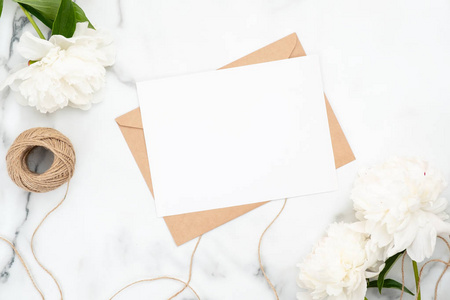 顶视图空白婚礼请柬在大理石背景上,白色牡丹花和麻线.