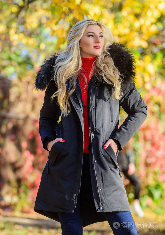 年轻人的现代服装穿着保暖外套的女孩站在公园自然背景下散焦一头金色