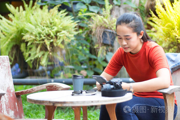 女人们在手机上玩互联网，还带着照相机