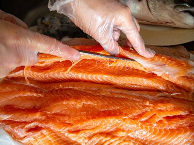 工人们在餐桌上用刀割鱼的特写镜头照片