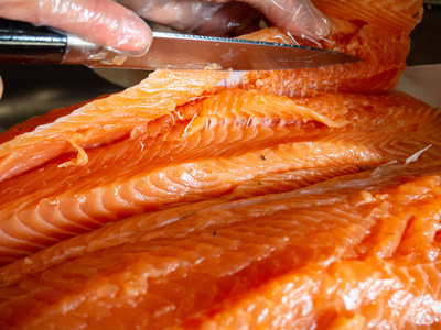 渔业工人工人们在餐桌上用刀割鱼的特写镜头照片