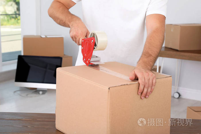 年轻工人在房间里打包纸板箱特写移动服务