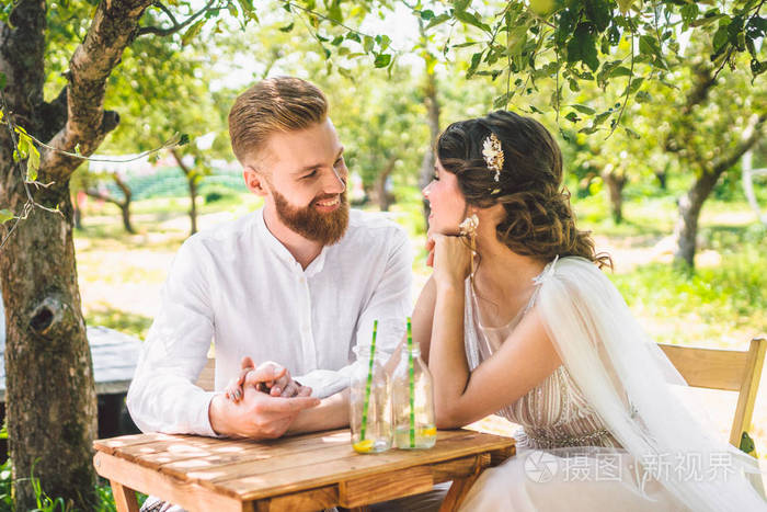 新郎新娘坐在树林里两个人的桌子旁.概念浪漫约会.
