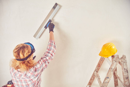 女工在屋内粉刷墙壁.工人粉刷房屋内的墙壁-装修修复.