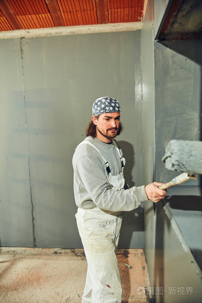 油漆工在室内用伸缩辊粉刷墙壁