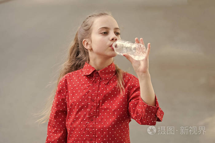 口渴的孩子喝塑料瓶里的淡水.小女孩正在用水瓶喝水.天然矿泉水解渴