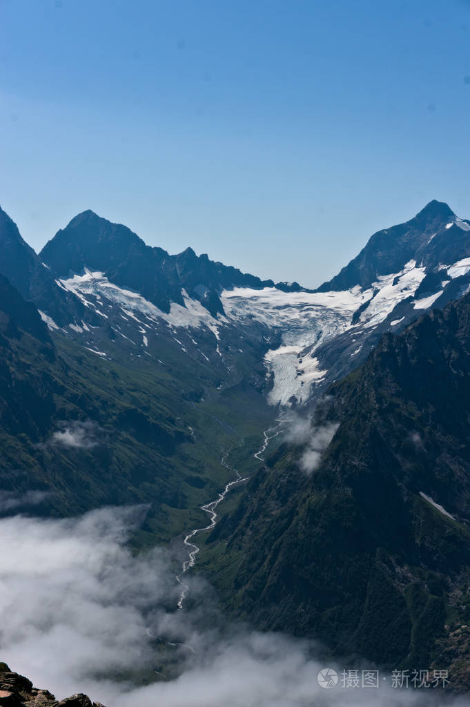 夏季高加索的多姆贝山脉白雪皑皑的山峰和绿色的山坡