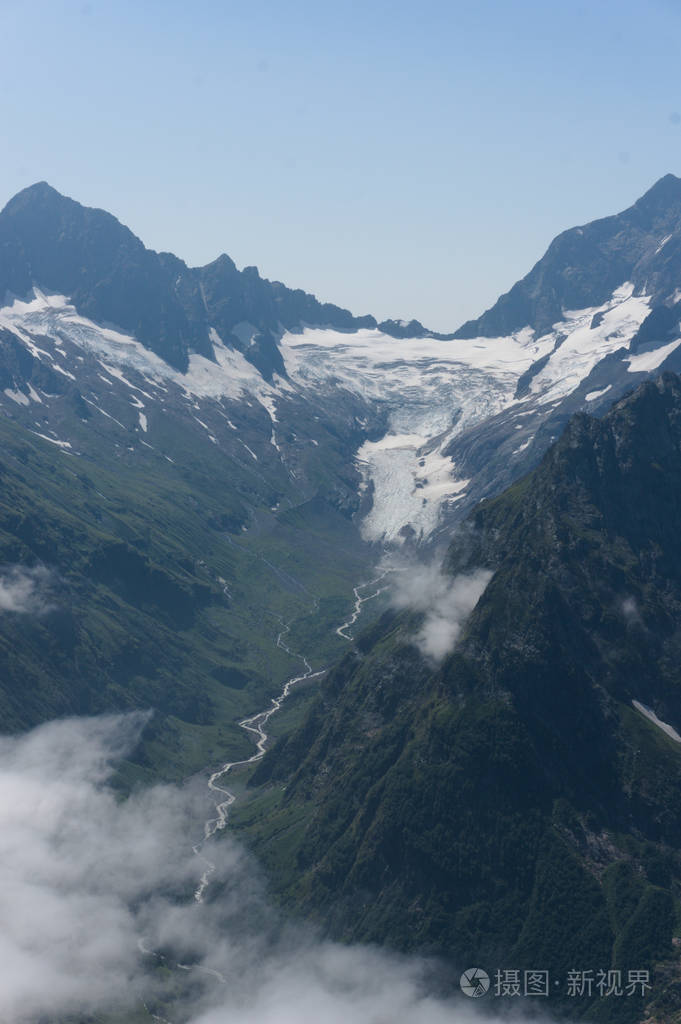 夏季高加索的多姆贝山脉白雪皑皑的山峰和绿色的山坡