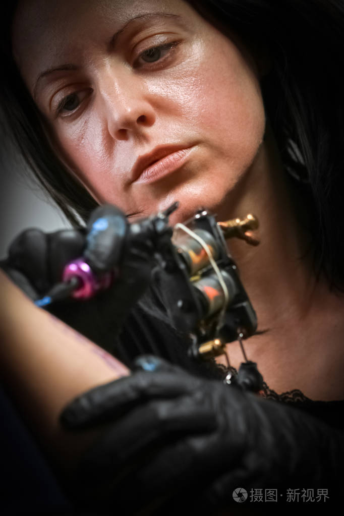 女纹身师在男人手臂上纹身