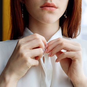 不认识的红头发女人解开白衬衫的扣子.照片