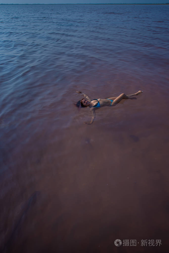 一个穿着蓝色比基尼的女人在盐湖里仰面游泳大自然的