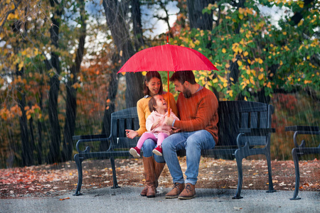 年轻的家庭享受秋雨图片