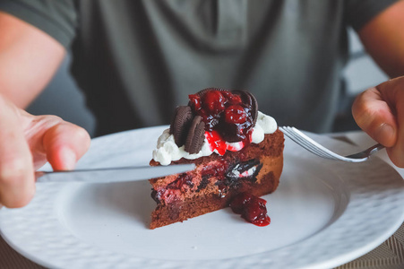 食物,垃圾食品,烹饪,烘焙和假日概念-男人手拿叉子吃巧克力樱桃蛋糕