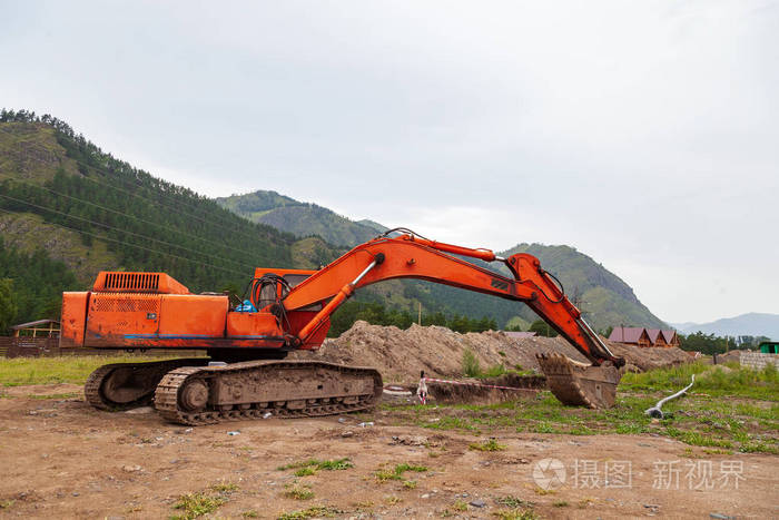 Large orange excavator with a lowered bucket during repair work 