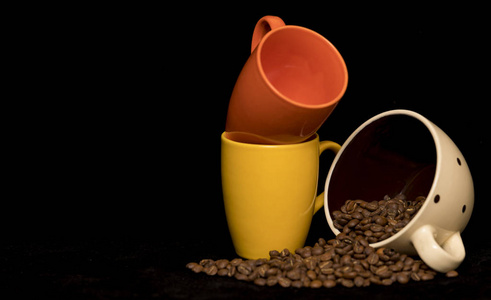 咖啡豆铺在咖啡杯的黑色背景上图片