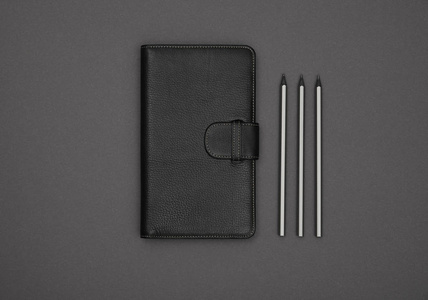 黑色皮革封面笔记本平放在灰色图片