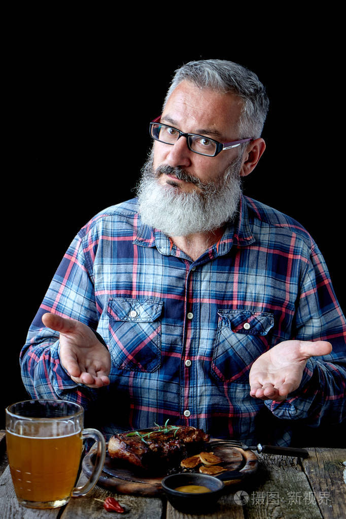 残暴的白发成年男子留着胡子,吃芥末牛排,喝啤酒,邀请吃饭,度假,节日