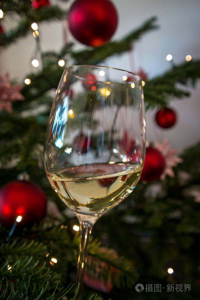 白色酒杯向右倾斜背景是圣诞树象征着庆祝的概念