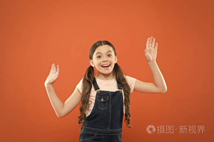看上去既高兴又兴奋.快乐的小女孩,橙色背景上带着可爱的微笑.开朗的