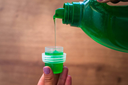 特写一个女人的手倒液体织物柔顺剂照片