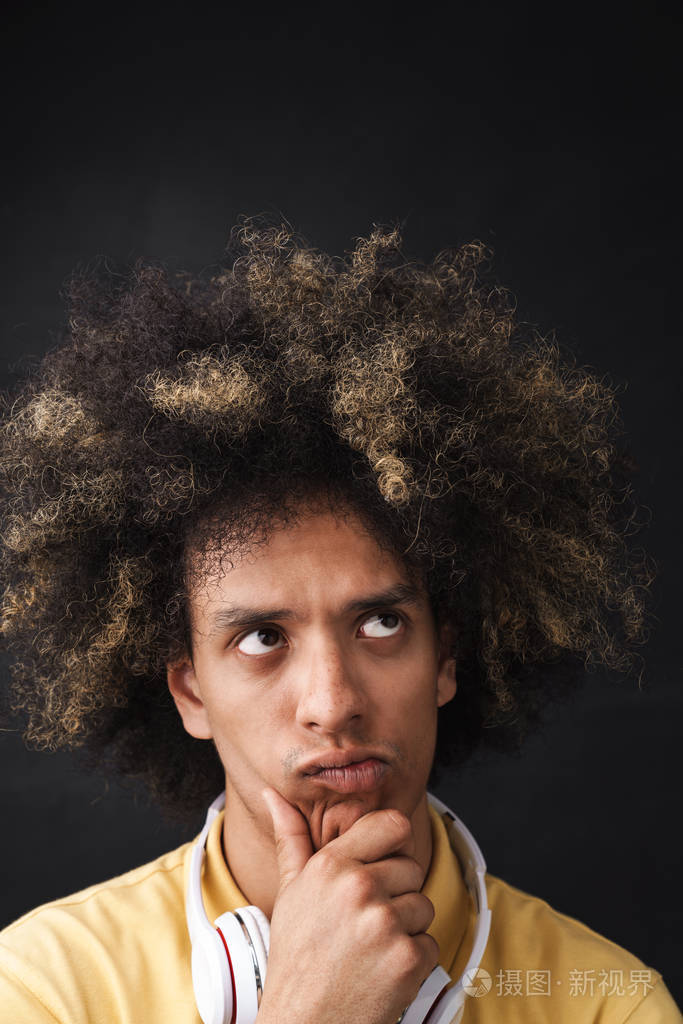 一个年轻,思想缜密,严肃认真的年轻人,戴着耳机在灰色的黑板墙上摆