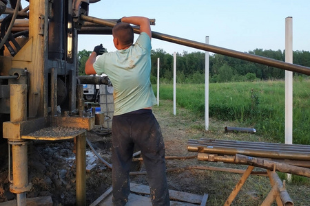 工人们在私人区域的水面上打井,装置安装在车上.照片