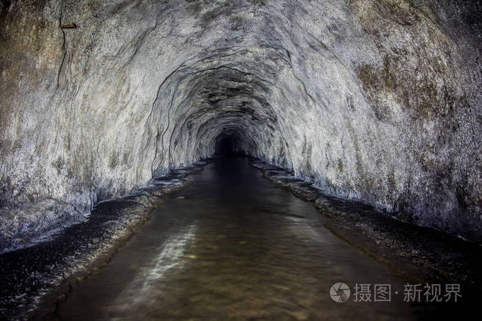一座废弃的老煤矿坑道被水淹没留下锈迹