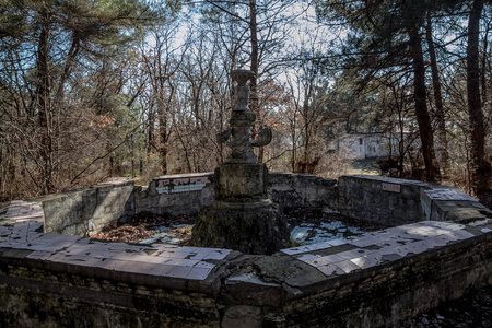 在杂草丛生的公园里,废弃的老喷泉照片