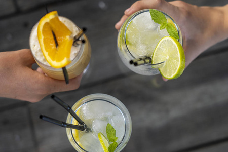 两个女孩拿着莫吉托和麦泰鸡尾酒.新鲜鸡尾酒杯,特写,俯视照片