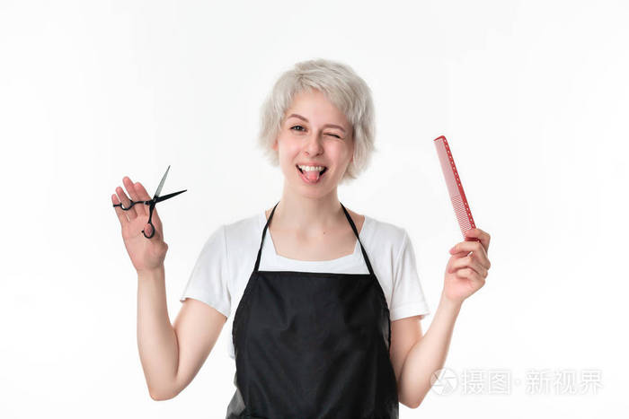 漂亮的理发师穿着白色t恤和黑色围裙手持黑色剪刀和红色发刷准备在
