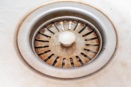 厨房水槽里陈旧的锈迹斑斑的钙化排水孔,有水垢和头屑照片