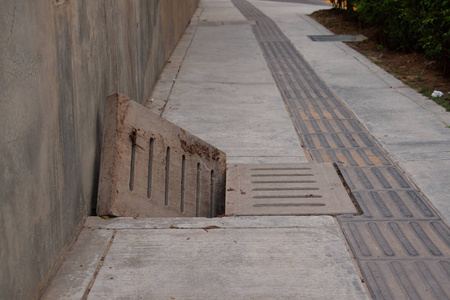 人行道上带混凝土明格栅的污水排水沟,下水道.照片