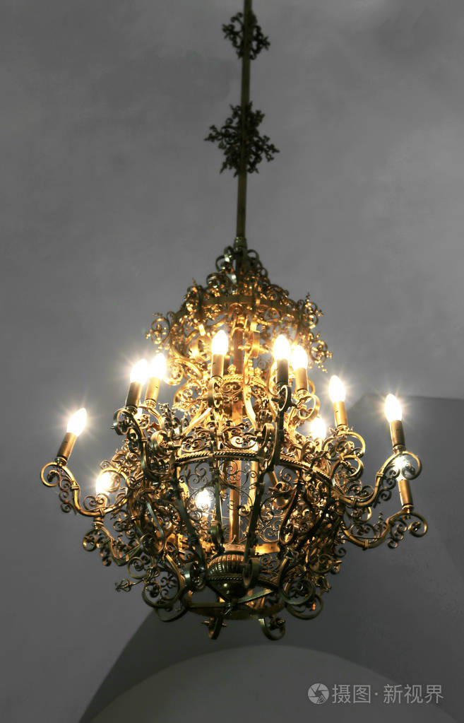 古老的中世纪吊灯和现代灯泡在旧城堡古今交融的概念