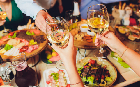 一组人在博克背景前用葡萄酒或香槟碰杯的特写镜头.老年人的手照片