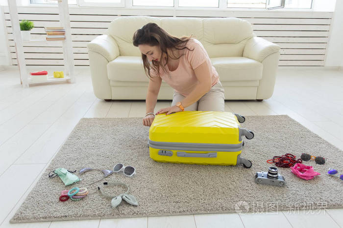 旅行和旅行的概念-年轻的女人在家里的卧室里收集一个手提箱,很多东西