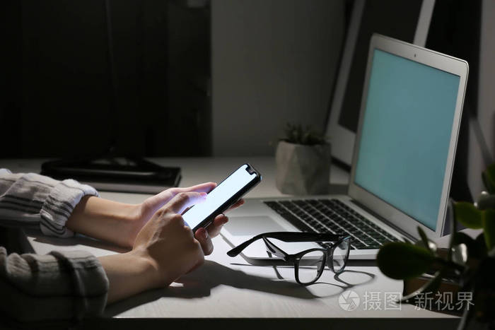 晚上拿着手机在桌边工作的女人