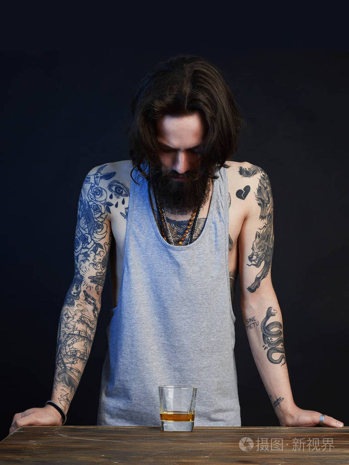 有胡子和纹身的醉汉一杯威士忌