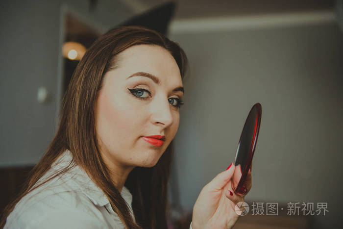 浓妆艳抹的女人手里拿着一面镜子