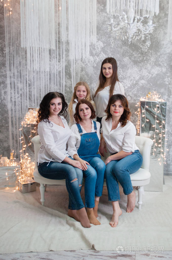 一群漂亮的女孩庆祝圣诞节,新年.房间里的女孩们坐在花环背景下的白色