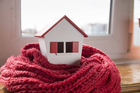 温暖家庭带暖气冬天的房子-暖气系统概念和寒冷的雪天,带针织帽子的