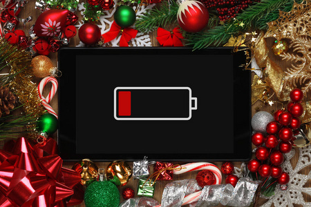 电池电量低的平板电脑,周围有圣诞装饰照片