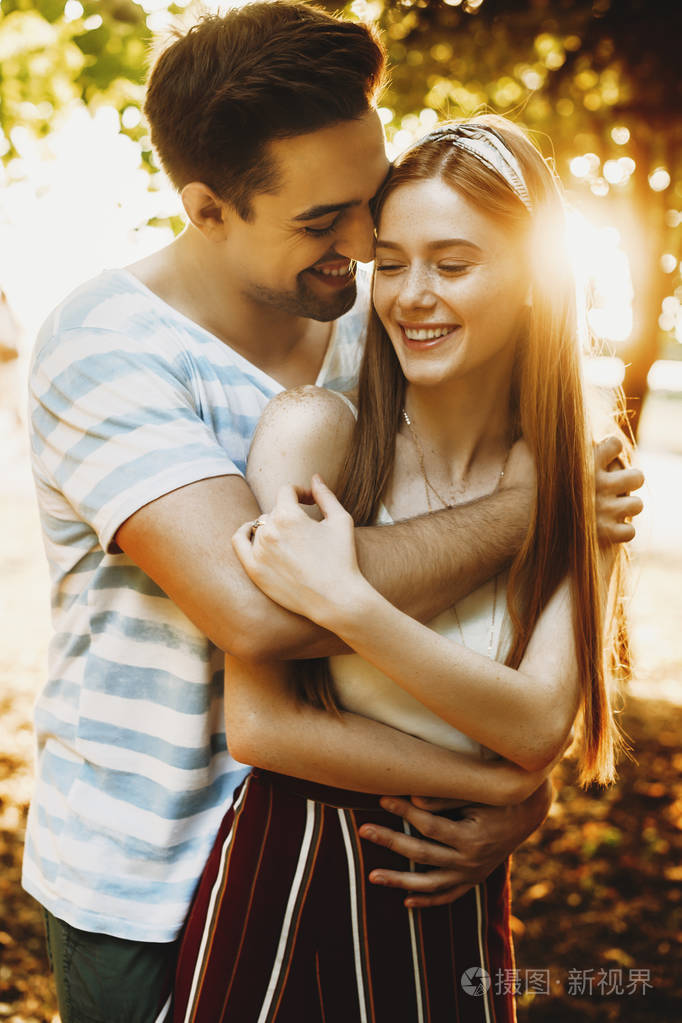 浪漫的年轻情侣在公园里拥抱快乐跑车