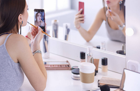 美女博主对着镜子用智能手机拍摄化妆教程 照片