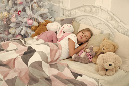 熟睡的孩子.小孩子睡在圣诞树旁.小女孩抱着玩具躺在床上.
