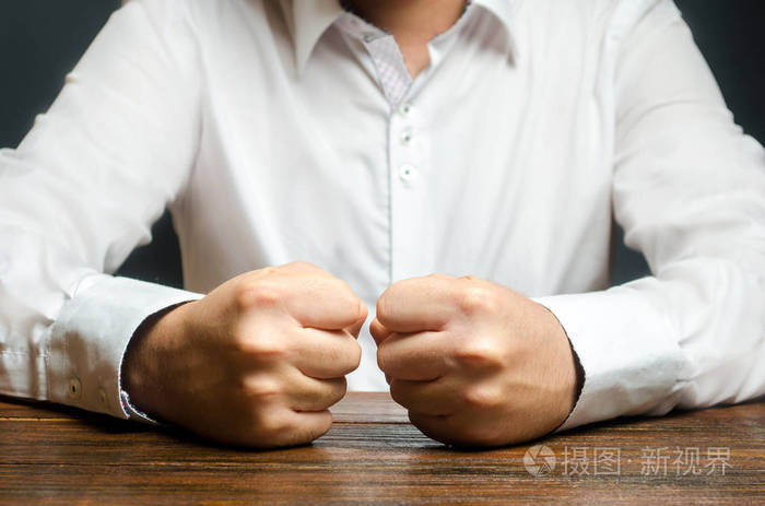 一个男人把紧握的拳头放在桌子上.忍耐的终结.这是无法忍受的.