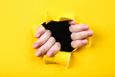 手在黄纸上撕洞照片