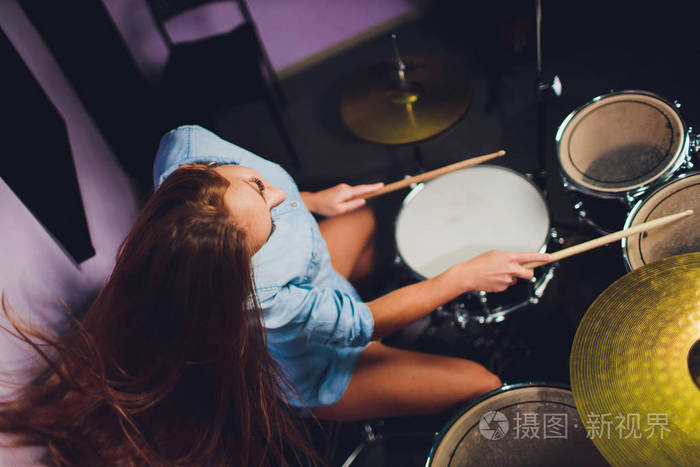 一位女鼓手在舞台上打鼓的照片